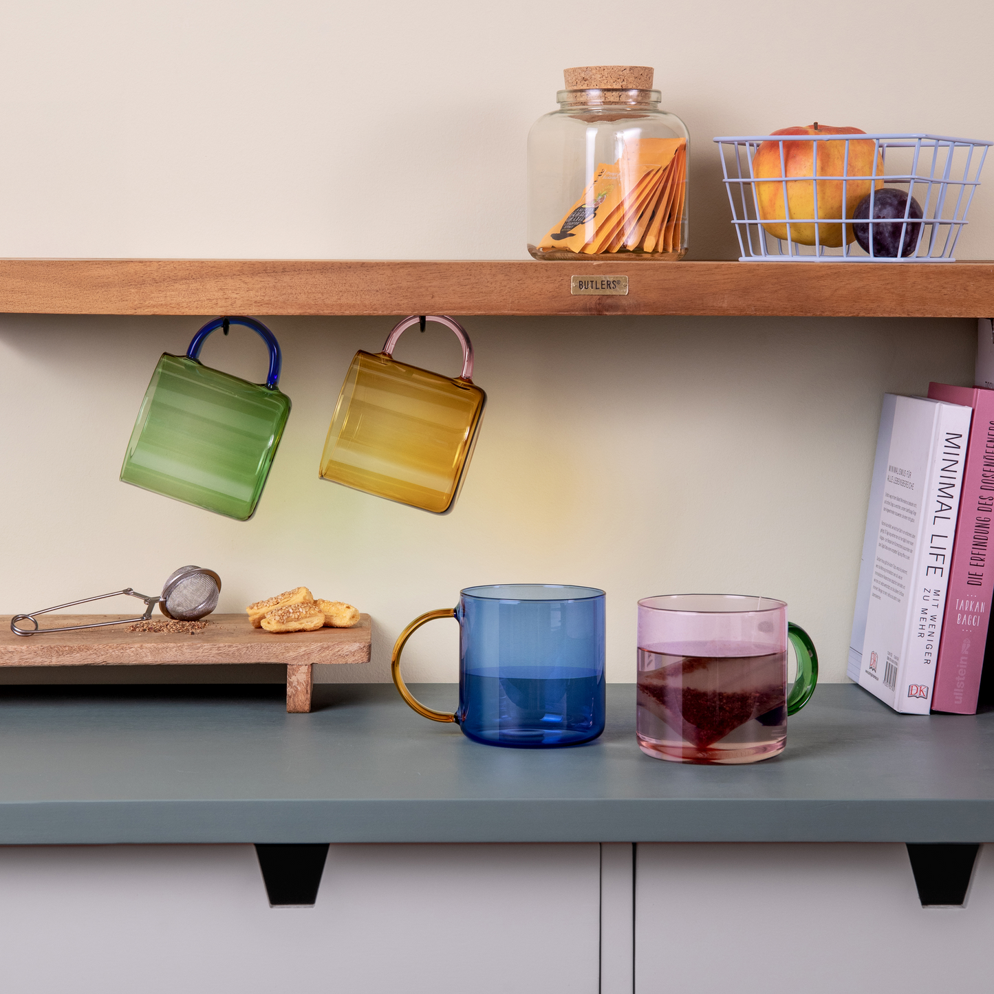 Colorful glass mugs on a shelf with a neutral background