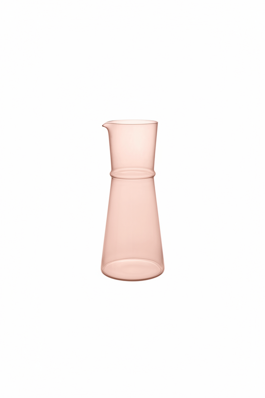 A translucent pale pink glass carafe with a wide body, narrow neck, and small pouring spout, centered on a solid green background.